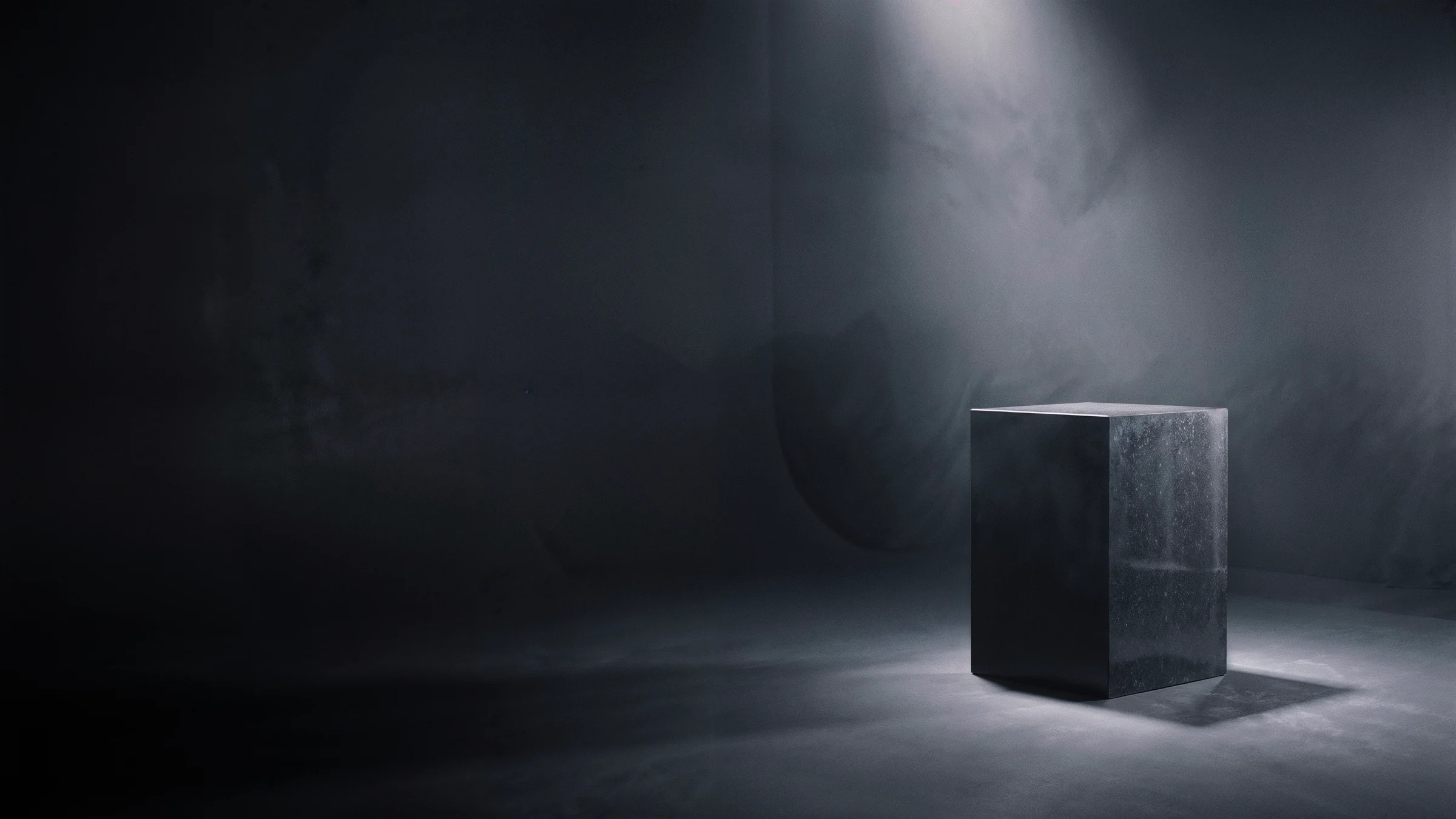 The studio at night: aluminium cube studies on black stone plinths under a single key light