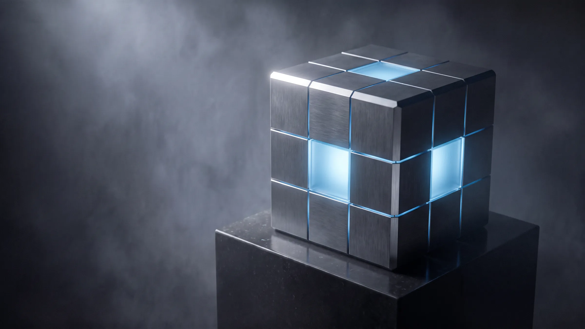 A brushed gunmetal cube with frosted glass centre tiles, lit from a core that shows through its seams